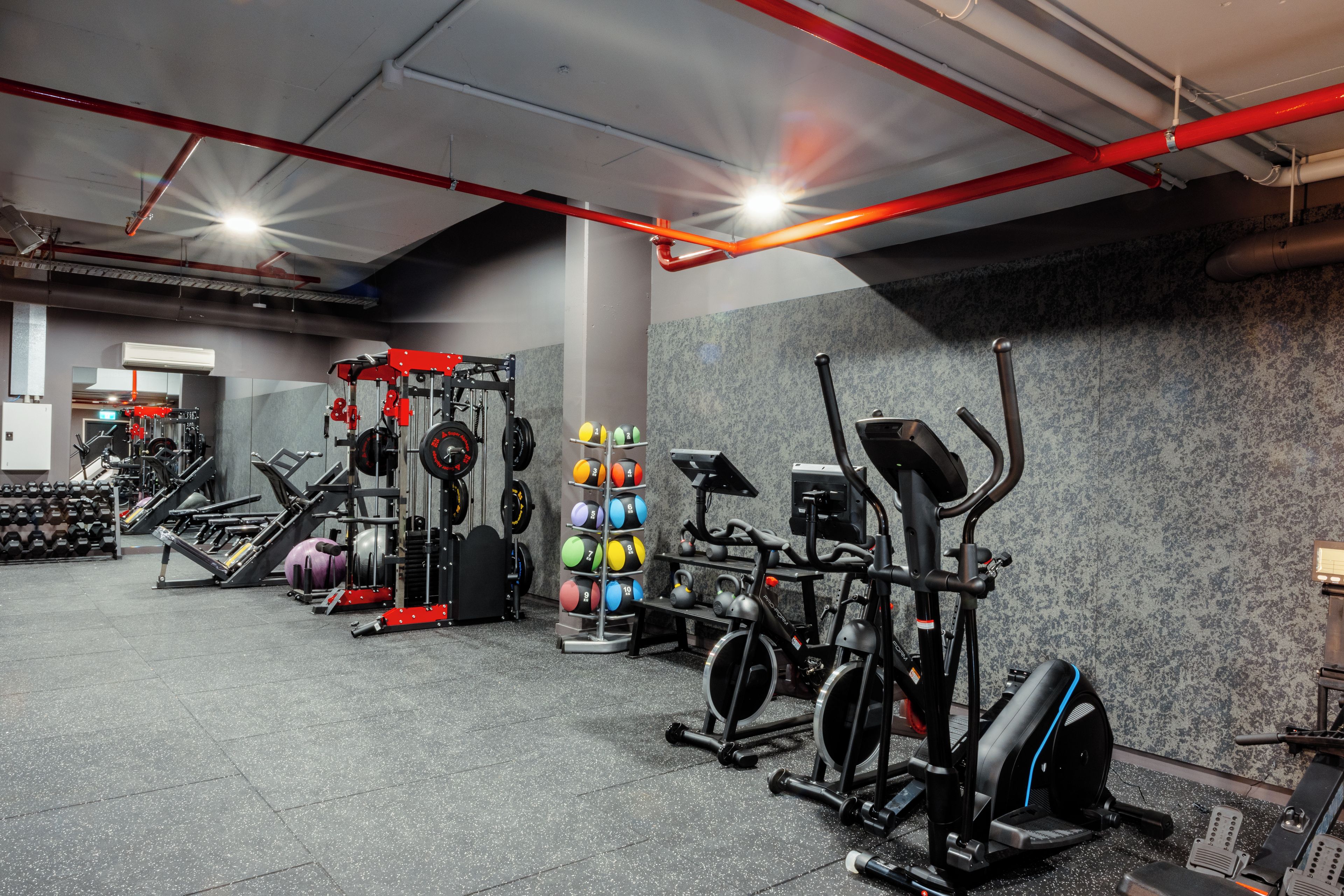 A gym with various exercise equipment, including weight machines, free weights, and cardio machines.