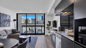 Un apartamento moderno con sala de estar, cocina y balcón con vistas a la ciudad.