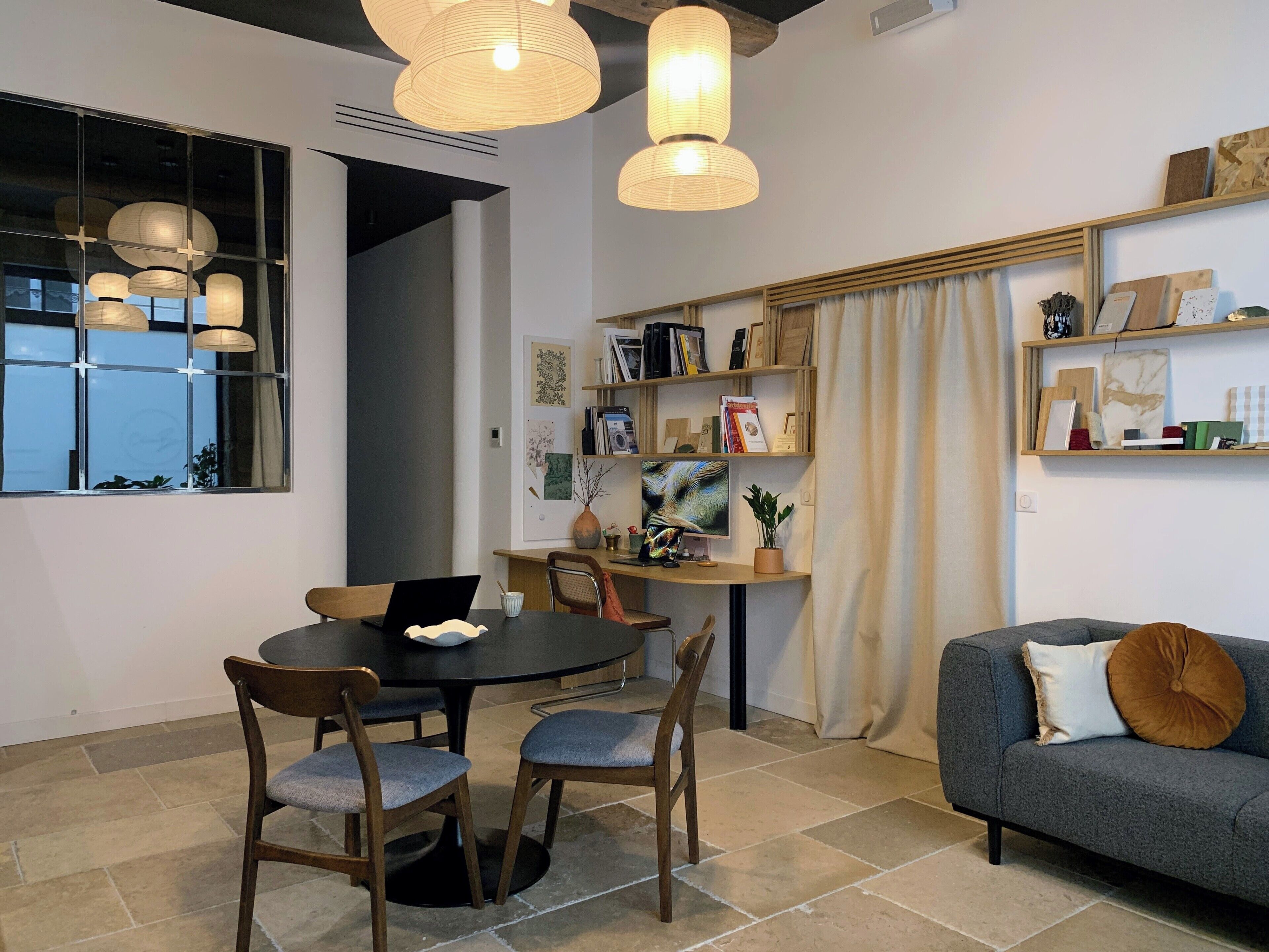 Uma sala de estar moderna com área de jantar, com uma mesa redonda, cadeiras, um sofá e uma estante.