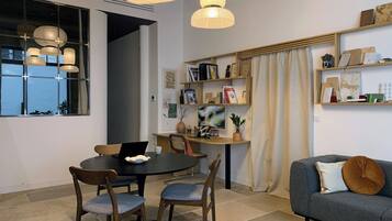 Uma sala de estar moderna com área de jantar, com uma mesa redonda, cadeiras, um sofá e uma estante.