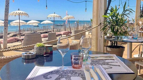 A table set for dining with a view of the beach and ocean.