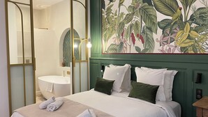 Habitación de hotel con cama, baño y un gran mural floral en la pared.