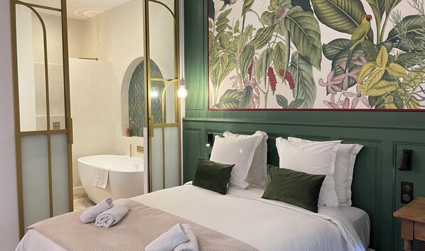 A hotel room with a bed, a bathroom, and a large floral mural on the wall.