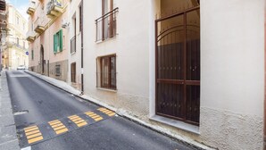 A narrow street with buildings on both sides, featuring balconies and large windows. - Beautiful apartment in Patti with WiFi (Patti)
