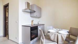 A compact kitchen with a stove, oven, sink, and a modern range hood. - Beautiful apartment in Patti with WiFi (Patti)