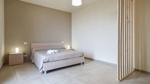 A minimalist bedroom with a bed, bedside tables, and a wooden partition. - Beautiful apartment in Patti with WiFi (Patti)