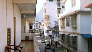 A narrow urban street with residential buildings, a balcony with a chair, and a parked car. - Yangshuo Culture House (Yangshuo)