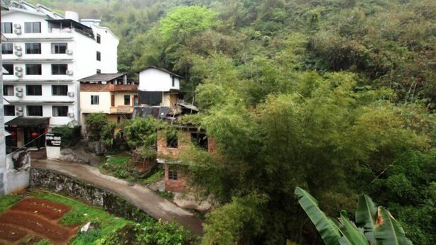 A residential area with buildings surrounded by dense greenery and a river. - Yangshuo Culture House (Yangshuo)