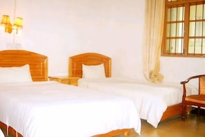 A hotel room with two wooden beds, a nightstand, a chair, and a window with curtains. - Yangshuo Culture House (Yangshuo)