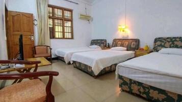 A hotel room with two single beds, a wooden chair, a desk, and a window with curtains.