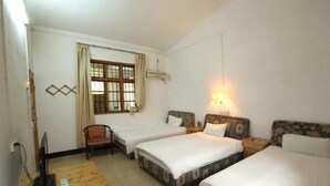 A hotel room with two beds, a desk with a computer, a chair, a window with curtains, and a wall-mounted air conditioner. - Yangshuo Culture House (Yangshuo)
