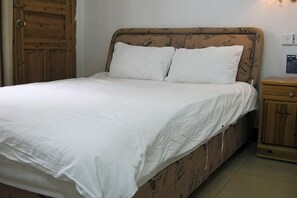 Un lit avec une tête de lit en bois, une table de chevet en bois et une petite armoire en bois.