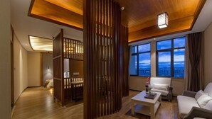 A modern living room with a wooden ceiling, a sofa, a coffee table, and a view of the cityscape through large windows.