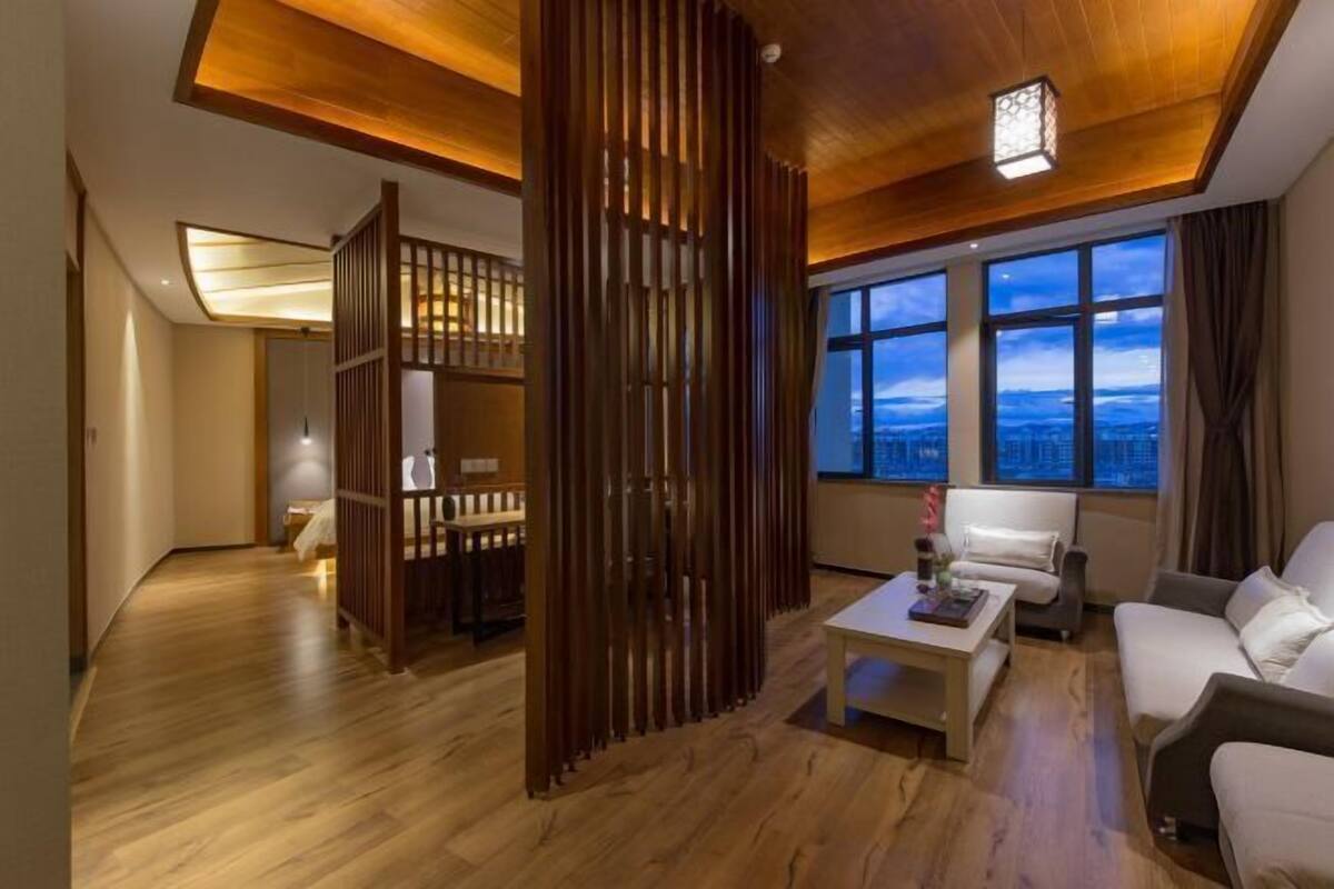 Een moderne woonkamer met een houten plafond, een bank, een salontafel en een uitzicht op de skyline door grote ramen.