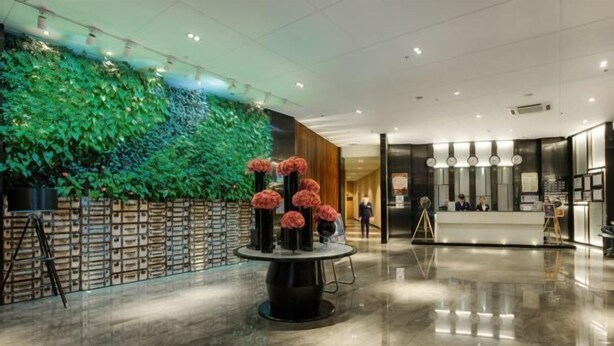 A lobby with a green wall, a reception desk, and a round table with vases.