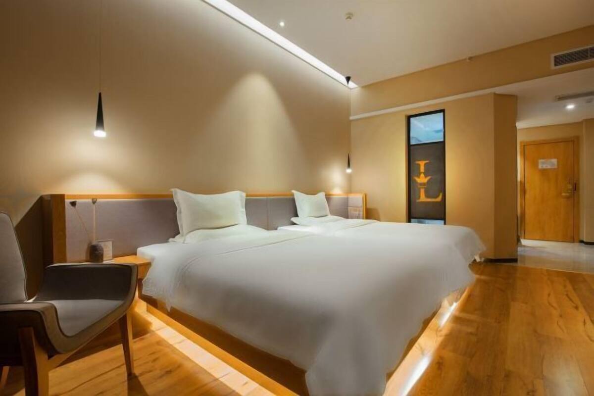 Een hotelkamer met een groot bed, een nachtkastje, een stoel en een deur.