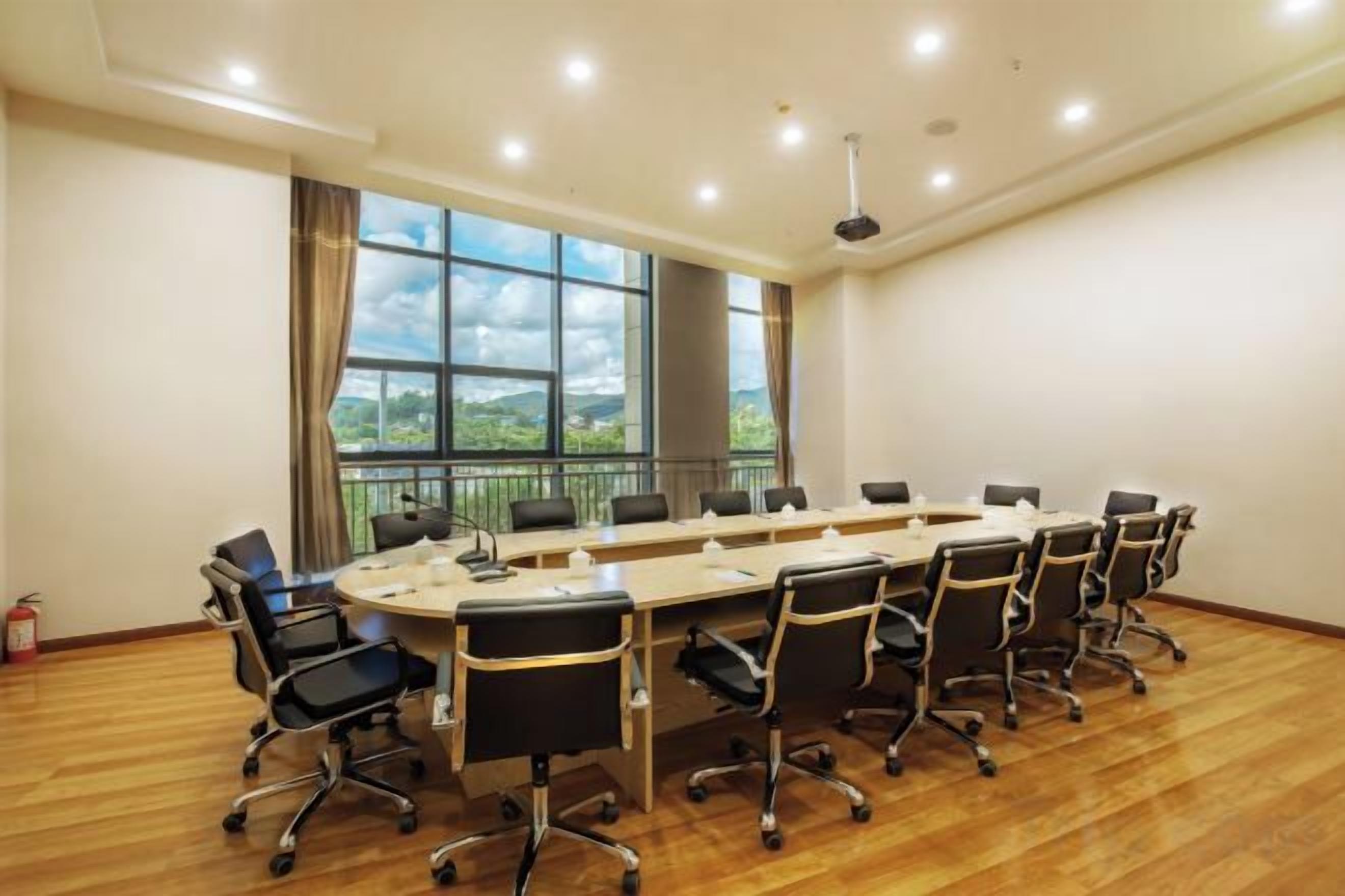 A conference room with a long table, chairs, and a view of the outdoors.