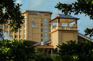 Un hotel con una torre destacada y fachada curva, rodeado de abundante vegetación.