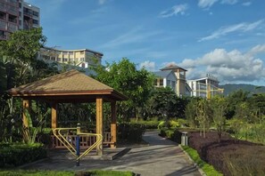 A gazebo with exercise equipment, a pathway, and buildings in the background.