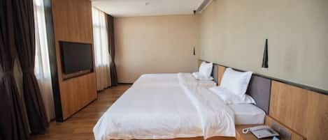 A modern hotel room with a large bed, a bedside table with a phone, and a TV mounted on the wall.
