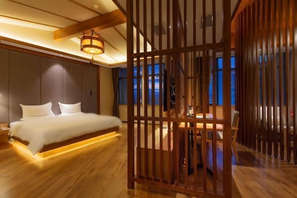 Ein Schlafzimmer mit einem Bett, Holzboden und Blick ins Freie.