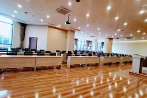 A conference room with rows of tables and chairs, large windows, and a podium.