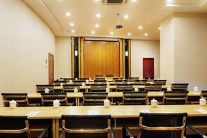 A conference room with multiple tables and chairs, a podium, and a red door in the background. - Lanmeishan Business Hotel (Pu'er Simao Airport) (Pu'er)
