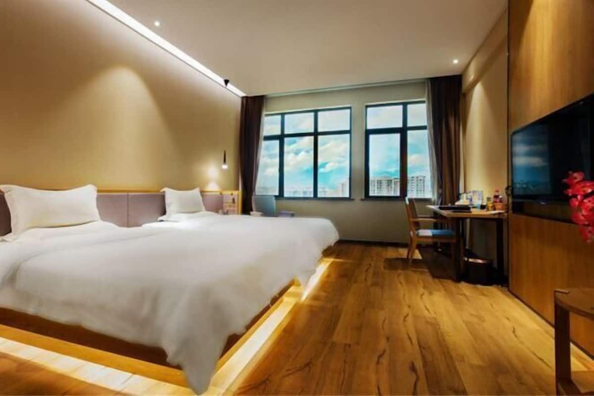 Hotelkamer met een groot bed, een bureau, een stoel, een televisie en een raam met uitzicht op de stad.