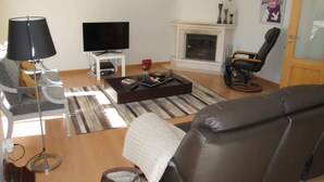 Una sala de estar con sofá, televisión, chimenea y lámpara.