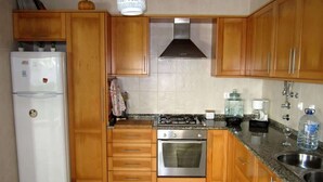 Una cocina con gabinetes de madera, estufa, horno y refrigerador.