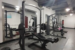 A gym with weightlifting equipment, benches, and a mirror. - Jinqiu Courtyard Hotel (Shaowu)