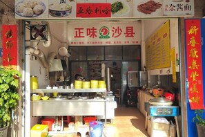 A food stall with a signboard, cooking equipment, and various food items displayed. - Jinqiu Courtyard Hotel (Shaowu)