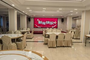 A conference room with round tables and chairs, a large screen displaying text, and a stage area. - Jinqiu Courtyard Hotel (Shaowu)