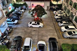 A parking lot with multiple cars and a tree in the center. - Jinqiu Courtyard Hotel (Shaowu)