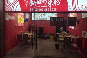 A restaurant with a red interior, multiple tables, and chairs. - Jinqiu Courtyard Hotel (Shaowu)