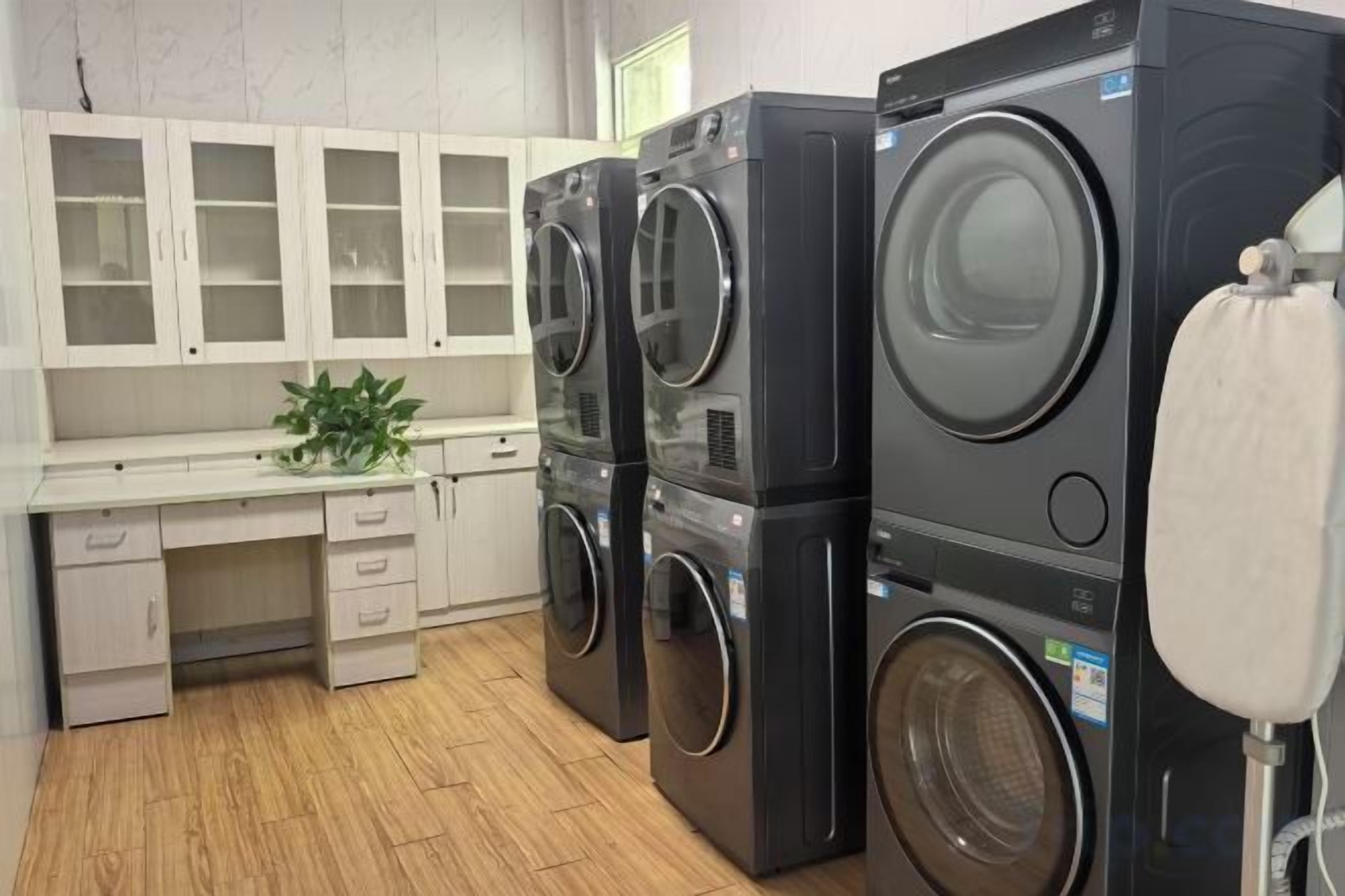 A laundry room with stacked washers and dryers, a sink, and cabinets.