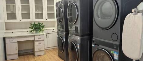 A laundry room with stacked washers and dryers, a sink, and cabinets.