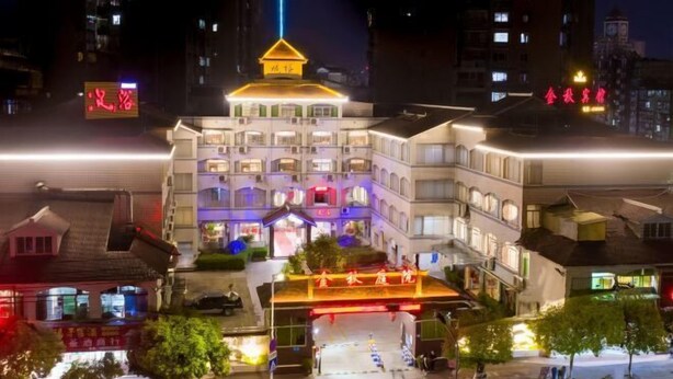 Un hotel de varios pisos con una entrada destacada y señalización iluminada.