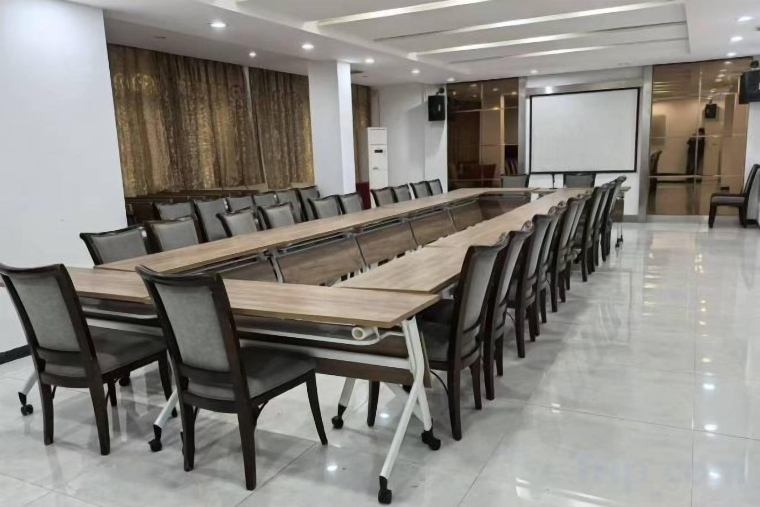 A conference room with a long table, chairs, a projector screen, and a whiteboard.