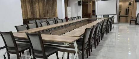 A conference room with a long table, chairs, a projector screen, and a whiteboard.