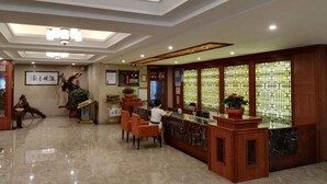 Un vestíbulo de hotel con mostrador de recepción, zona de estar y elementos decorativos.