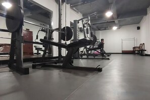 A gym with weightlifting equipment, a bench press, and a squat rack. - Jinqiu Courtyard Hotel (Shaowu)