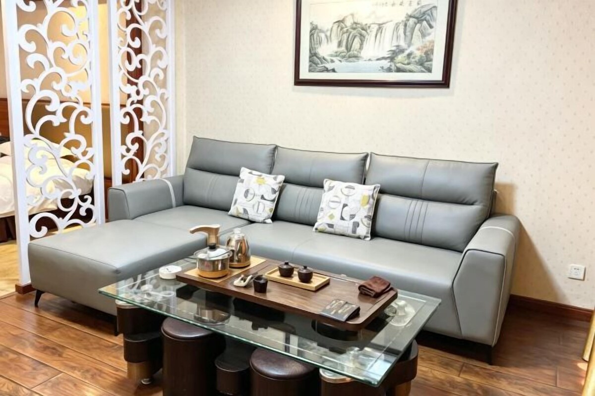 Una sala de estar con un sofá gris, una mesa de centro de vidrio y almohadones decorativos.
