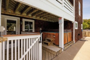 A wooden deck with a white railing, a hot tub, and a covered porch area. - Salty Cs: Stunning Oceanside Home with Private Pool, Hot Tub and Pool Table! (Nags Head)