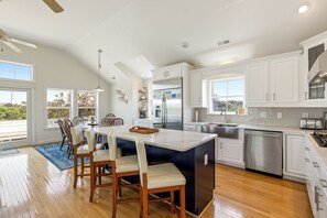 Una cocina moderna con armarios blancos, electrodomésticos de acero inoxidable y una isla grande con asientos.