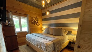 Een houten slaapkamer met een bed, bedlampen en een raam.