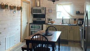 Een keuken met houten wanden, een kroonluchter, een eettafel met stoelen en moderne apparatuur.