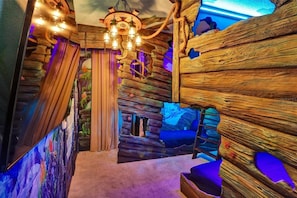 Une pièce au décor rustique, avec des éléments en bois, un lustre et un lit bleu.
