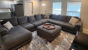 A living room with a sectional sofa, ottoman, and a ceiling fan. - Lakefront in Duck Creek with Private Dock, 2 Units (Afton)