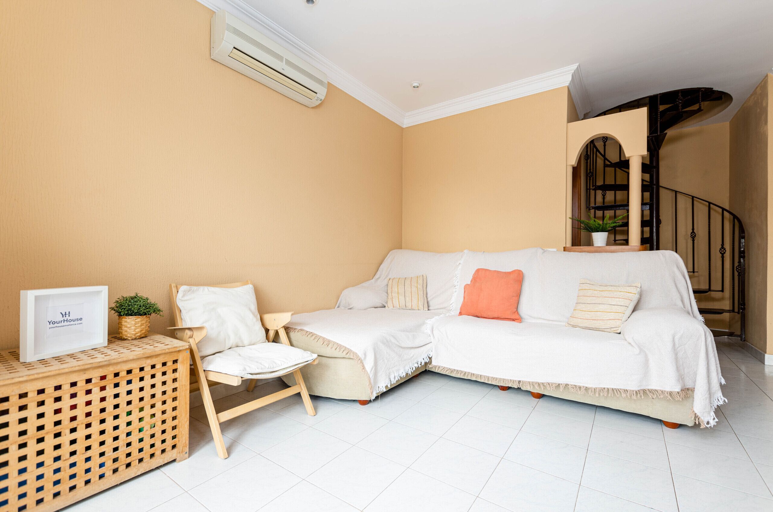 A living room with a beige sofa, a small wooden side table, and a chair.